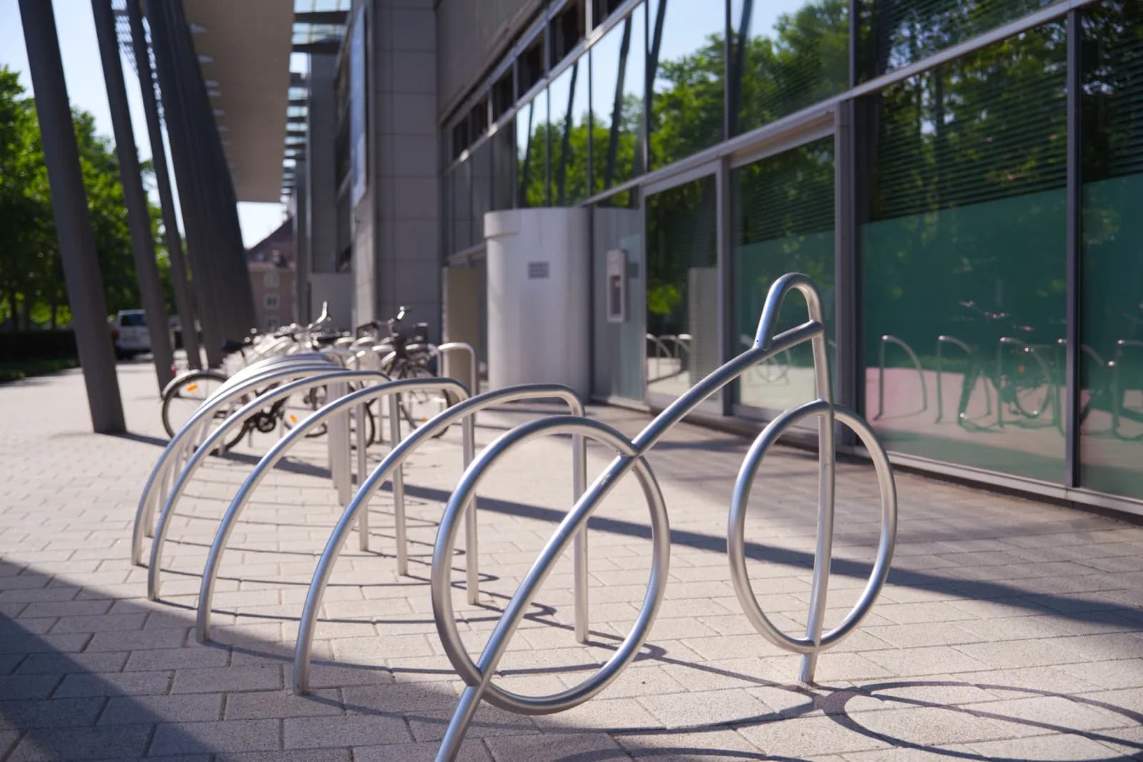Stainless steel bike racks shaped like bicycles installed outside a modern healthcare building in Canada