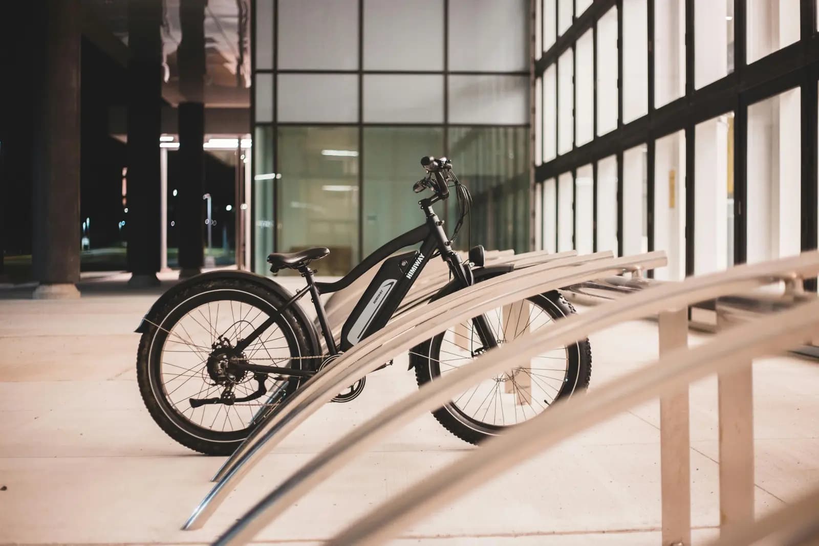 Electric bike parked at a modern bike rack outside a hotel building at night in Canada