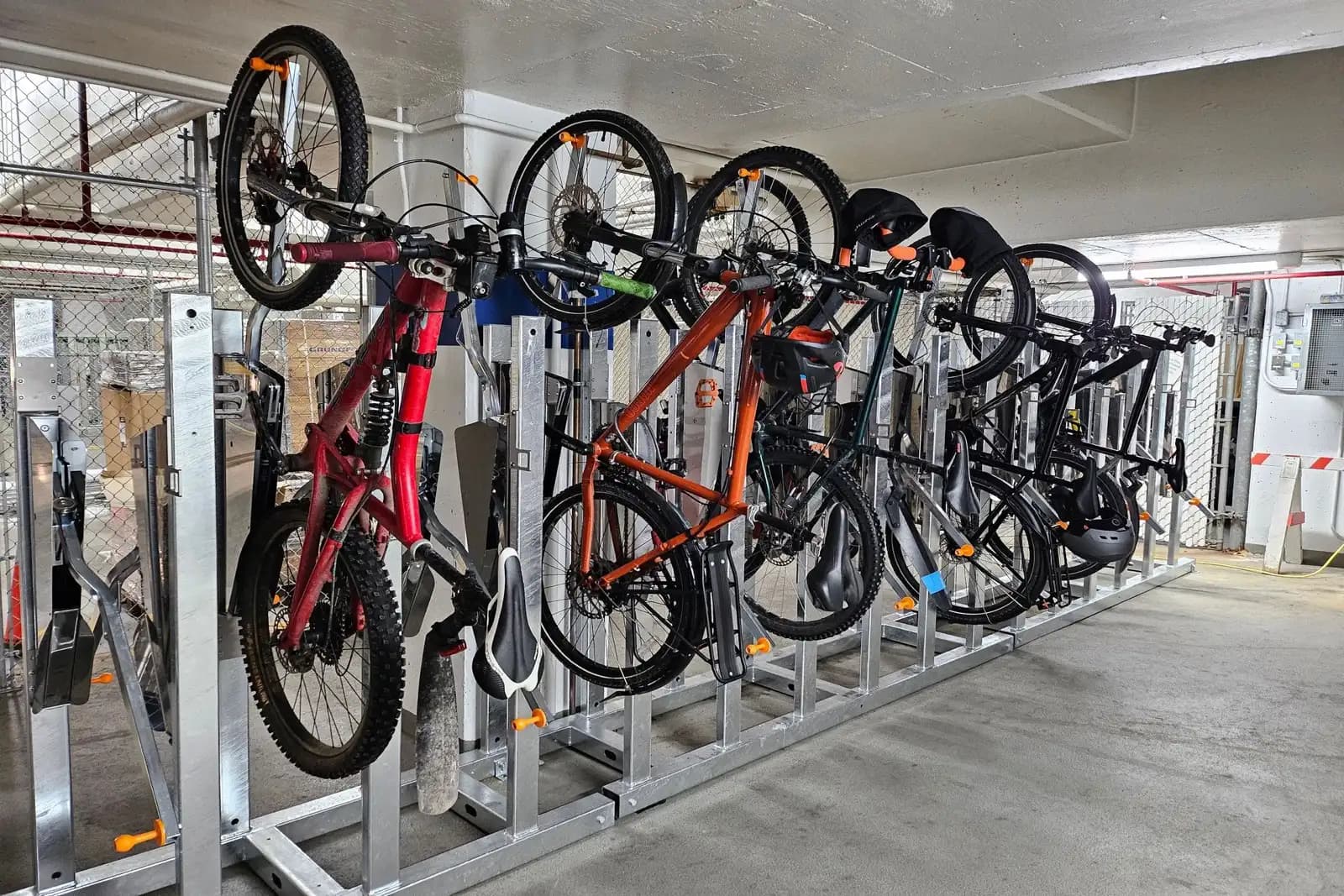 Vertical bike racks with multiple bicycles stored upright in a secured parking garage bike cage in Canada
